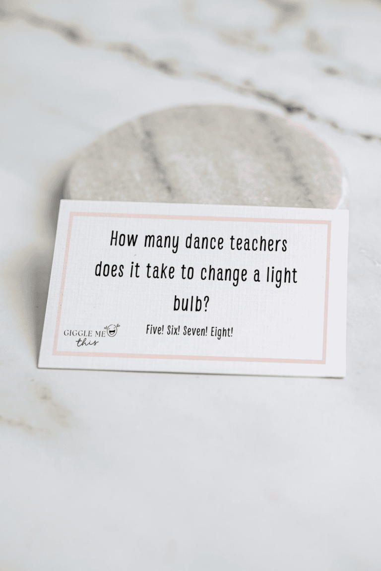 A card on a marble surface reads: “How many dance teachers does it take to change a light bulb? Five! Six! Seven! Eight!”—one of the classic jokes about dance.